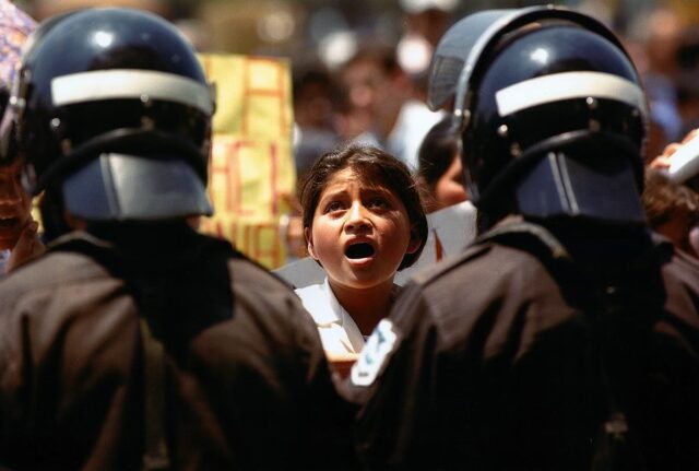 A student signing the Guatemalan national anthem in front of the police riot