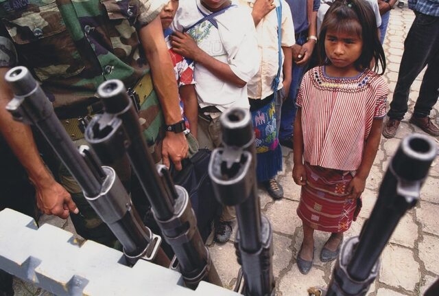 A Guatemalan aboriginal girl looking at weapons surrended by Civil Police patrols.