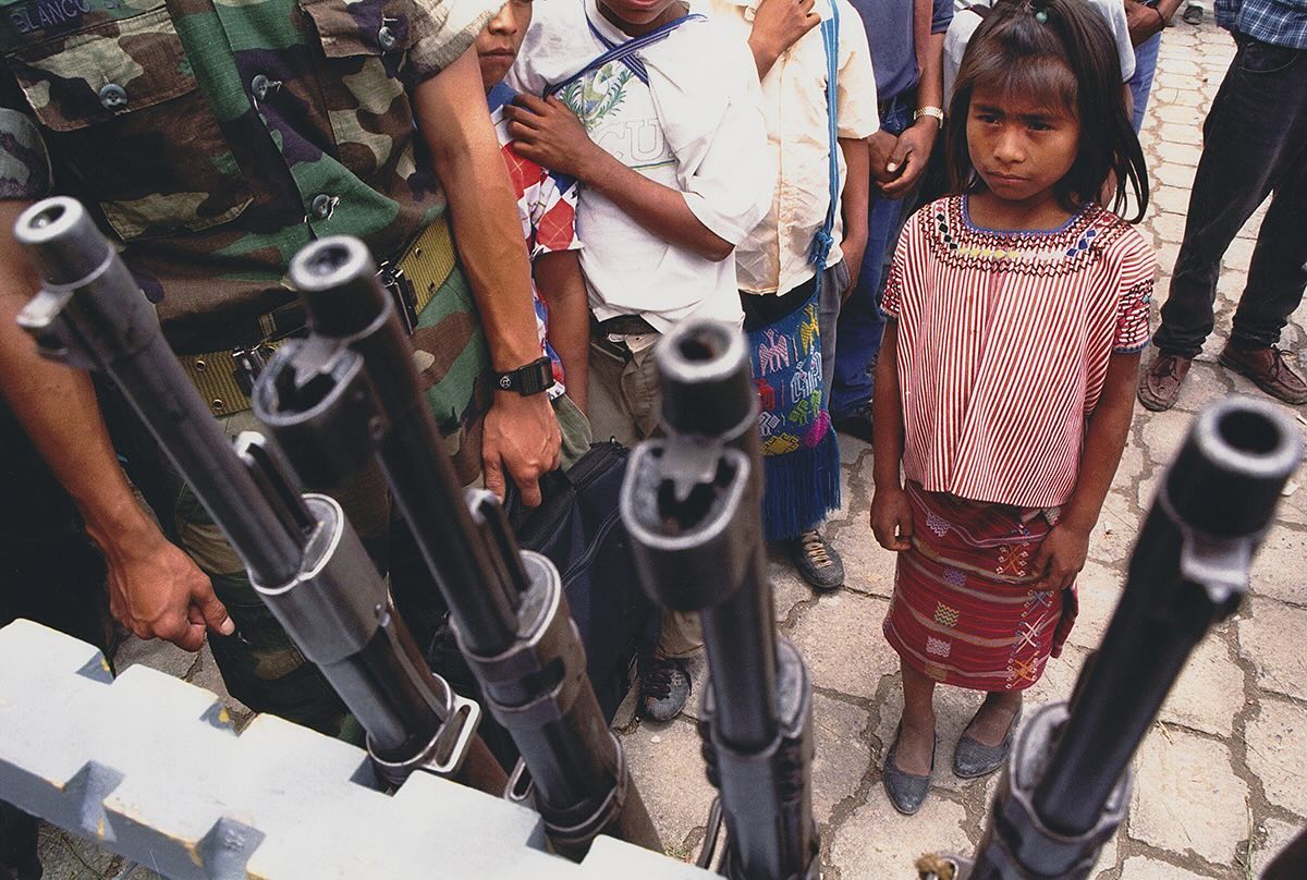 A Guatemalan aboriginal girl looking at weapons surrended by Civil Police patrols.