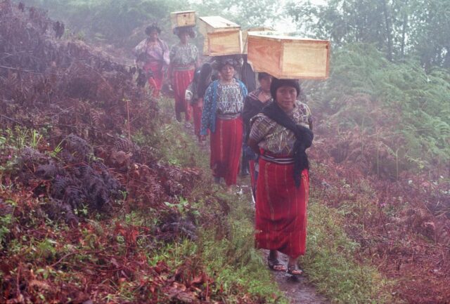 Guatemalan Ixil women carrying coffins over their heads with remains of victims of the civil war